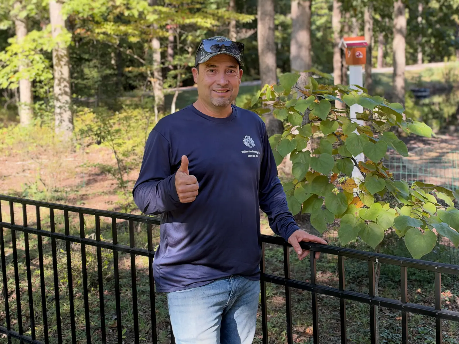 Willow Landscaping team member beside garden planting and a black railing